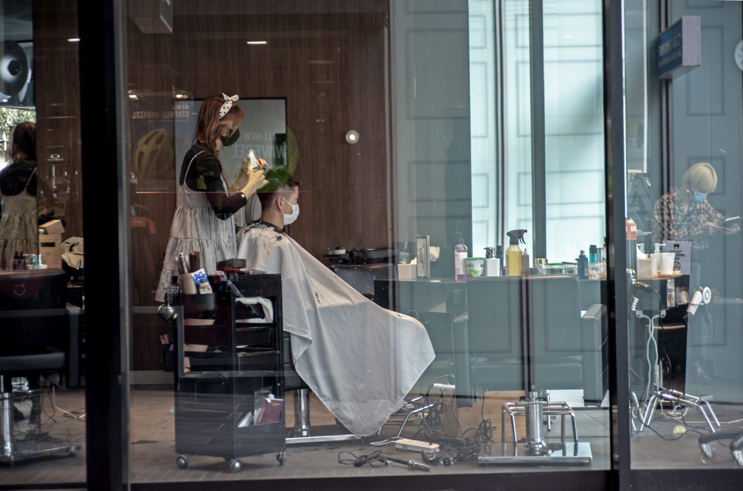 Barber, kobieta strzyże mężczyznę, podczas pandemii