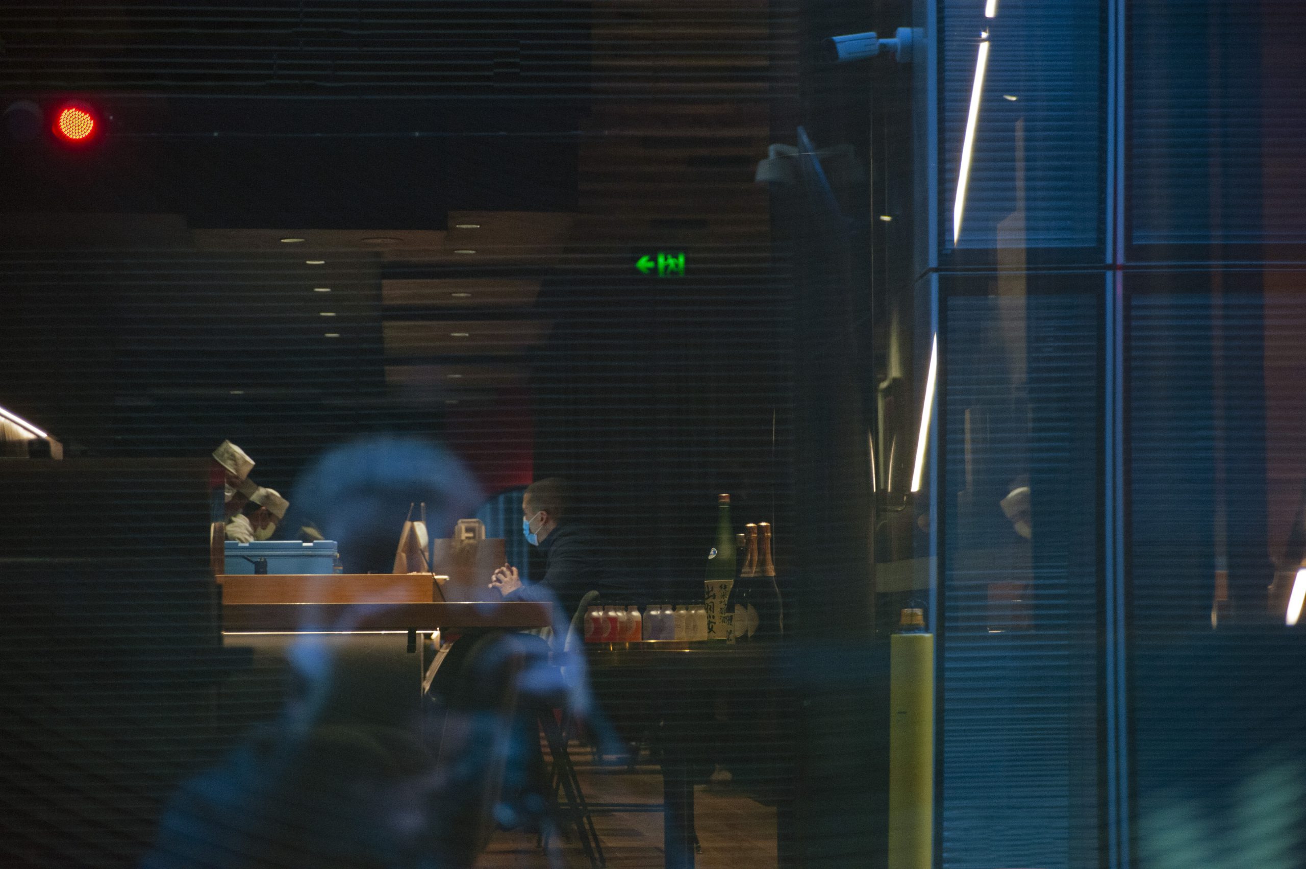 Wnętrze japońskiej restauracji, mężczyzna siedzący przy barze w maseczce
